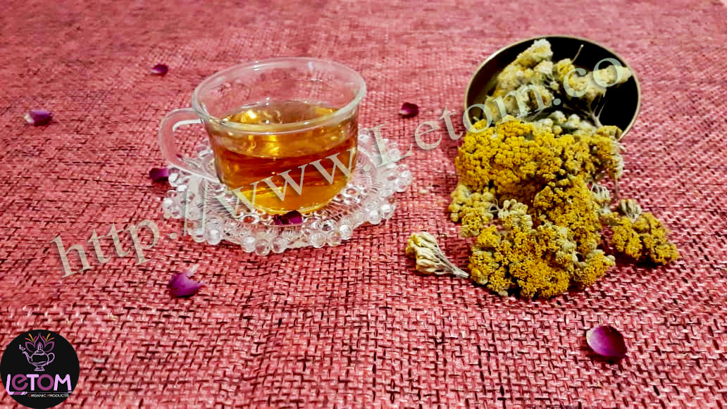A cup of yarrow tea next to a bowl of dried yarrow